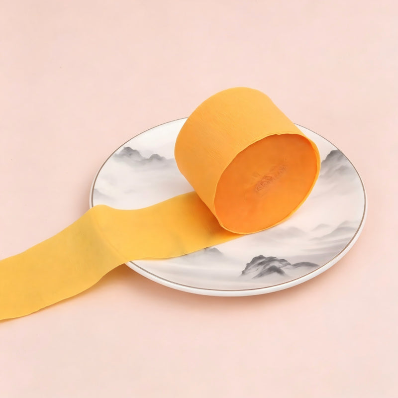 Crepe paper streamer light orange coiled roll extending strip