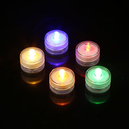 Submersible waterproof LED tea light multicolored glowing units on reflective black surface
